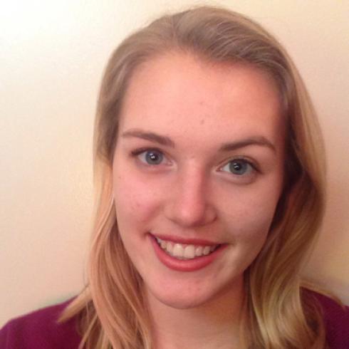 Smiling woman at scenic sunset viewpoint, city in background. This alt text was added with Al; accuracy may vary.