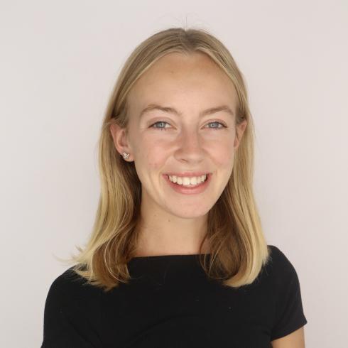 Amelia Kuiper similing in front of a plain background.