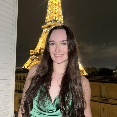 Hayley Clark smiling in front of the Eiffel Tower.