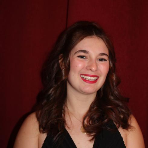 Sara Kurth smiling in front of a red background.