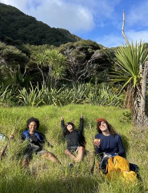 Three students laying in the grass while on a hike in New Zealand's mountains
