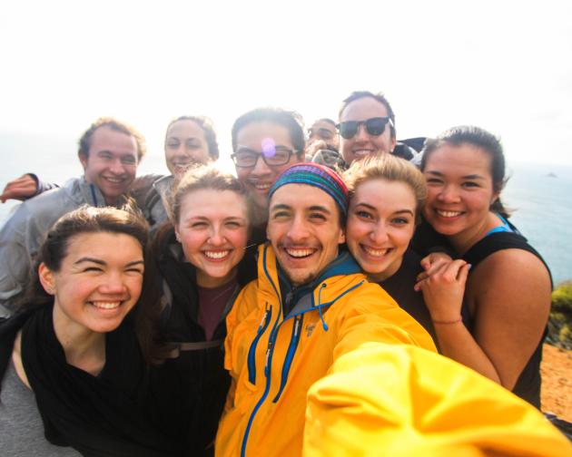 a group of students pose for a photo while backpacking on New Zealand's coast
