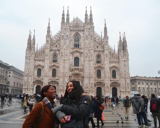 two students laugh while having their photo taken in front of Duomo di Milano