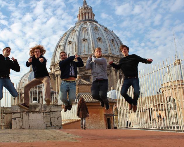 students jump to pose for a fun photo in front of St. Peter's Basilica
