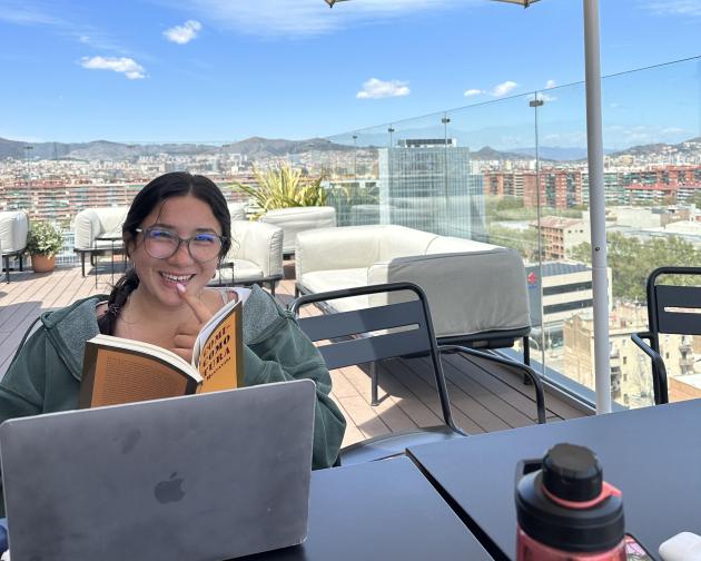 A student studding at the Social Hub in Barcelona, Spain. From the study space, there's a view of the Barcelona cityscape.