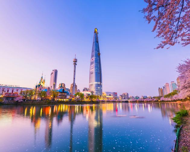 Seoul, South Korea's cityscape at sunset. The sky is pink, and in the foreground of the city is a body of water.