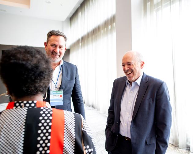 three people standign in a circle in front of a window laughing