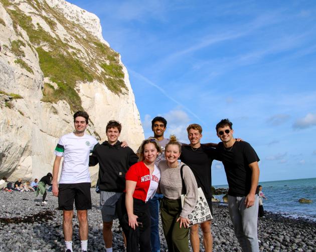group of students standing in a group on a beach smiling