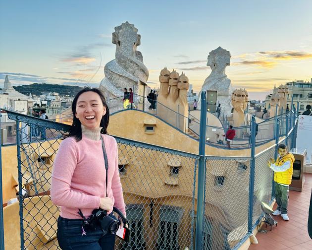 student standing on steps in front of colorful fence and textured buildings