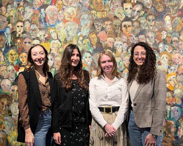 four students standing in front of painting