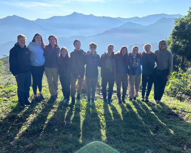 Group of people standing together with a background of mountains. 