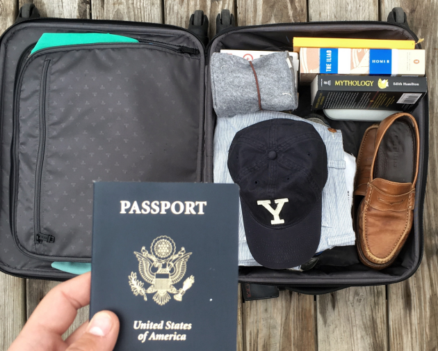Picture of open suitcase with Yale hat, shoes, passport, clothes, and books