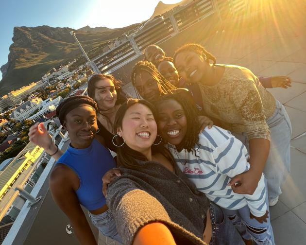 A group of beautiful ladies taking a selfie with the mountains and sun at the background