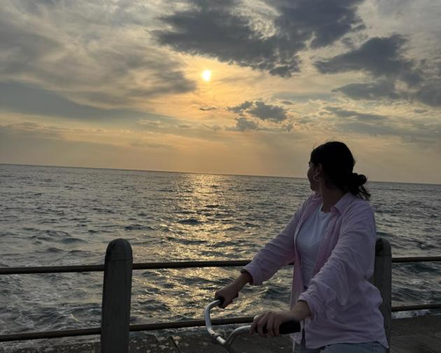 An image showing sunset and a person on a bicycle by the ocean 