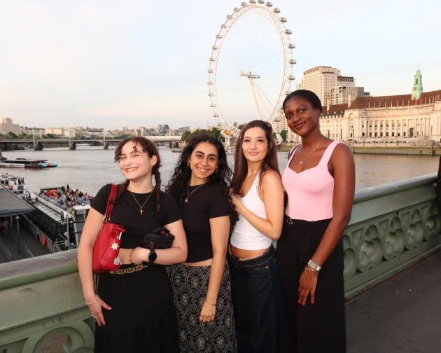 A group of friends smiling on a bridge in front of the London Eye
