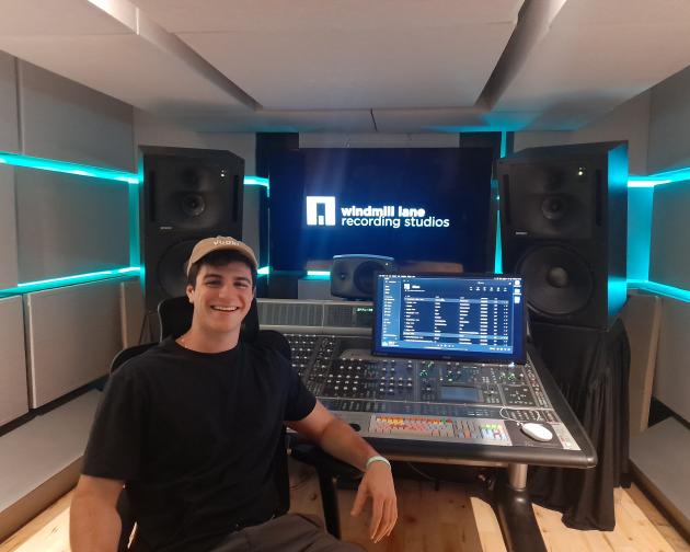 Male student standing in front of video screens in filming studio 