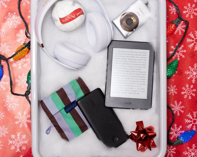 TSA bin filled with fake snow for the "Tech Lover" including a portable charger, a reusable tote bag, an e-reader, digital camera, and headphones