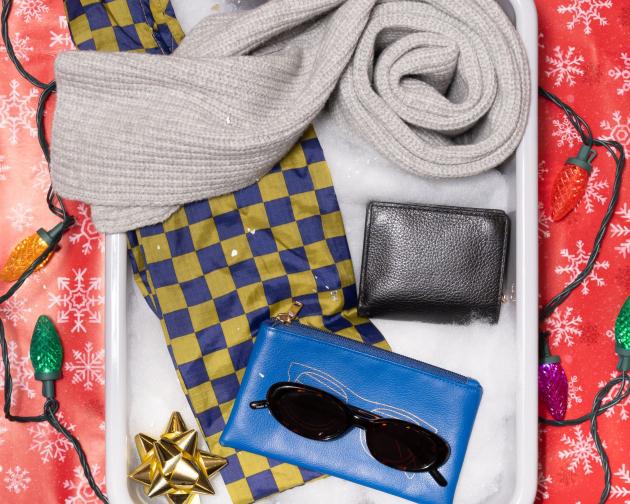 A TSA bin filled with fake snow for the "Style Icon" with a reusable tote bag, sunglasses, a wallet, and scarf