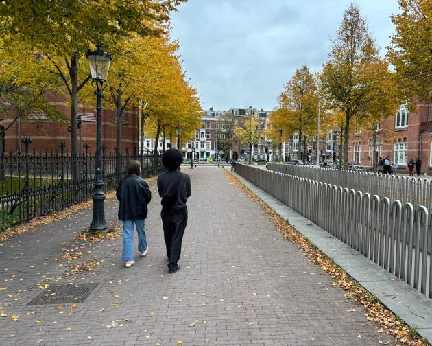 Two people walking on a sidewalk