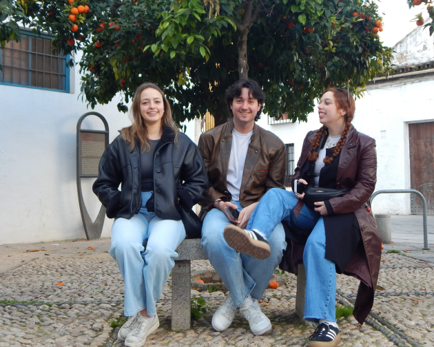 A group of friends smiling on the bench in front of a fruit tree in Madrid