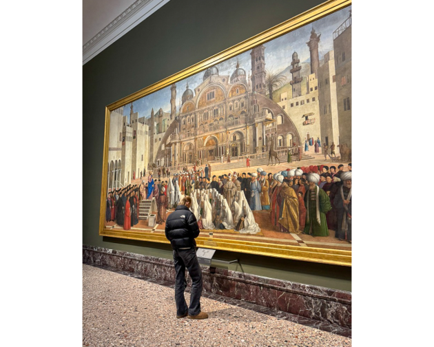 A person standing in front of the large painting St. Mark Preaching in Alexandria at the Pinacoteca di Brera in Milan.