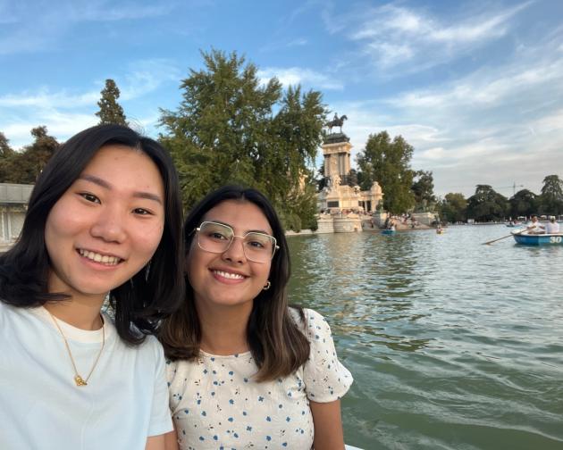 Two students smiling in front of the water at Retiro Park in Madrid, Spain