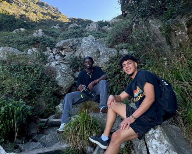 Two guys sitting on rocks in front of a blue sky in Cape Town.