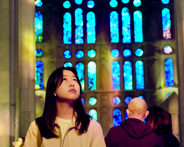 A student admiring the stunning stain glass windows inside La Sagrada Familia in Barcelona