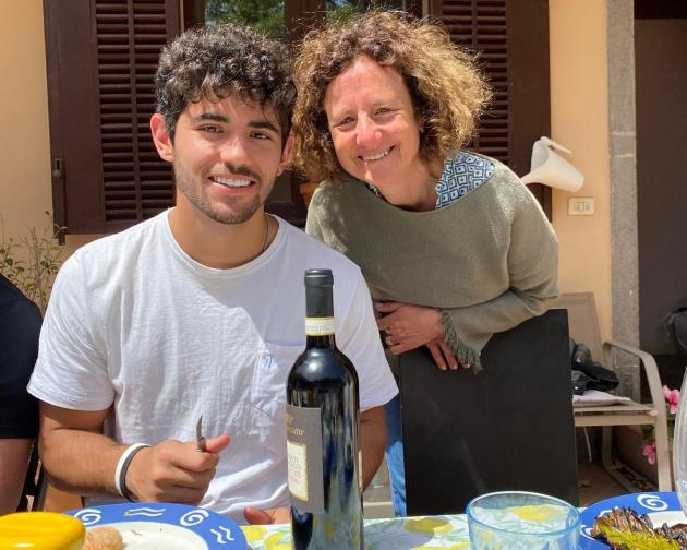 A student poses with his host mom at a picnic table.