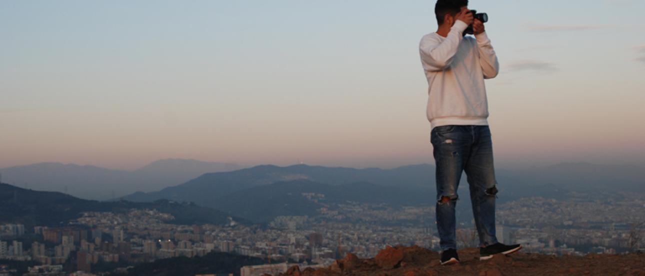 Christian Canizal holding up a camera in front of a sunset.