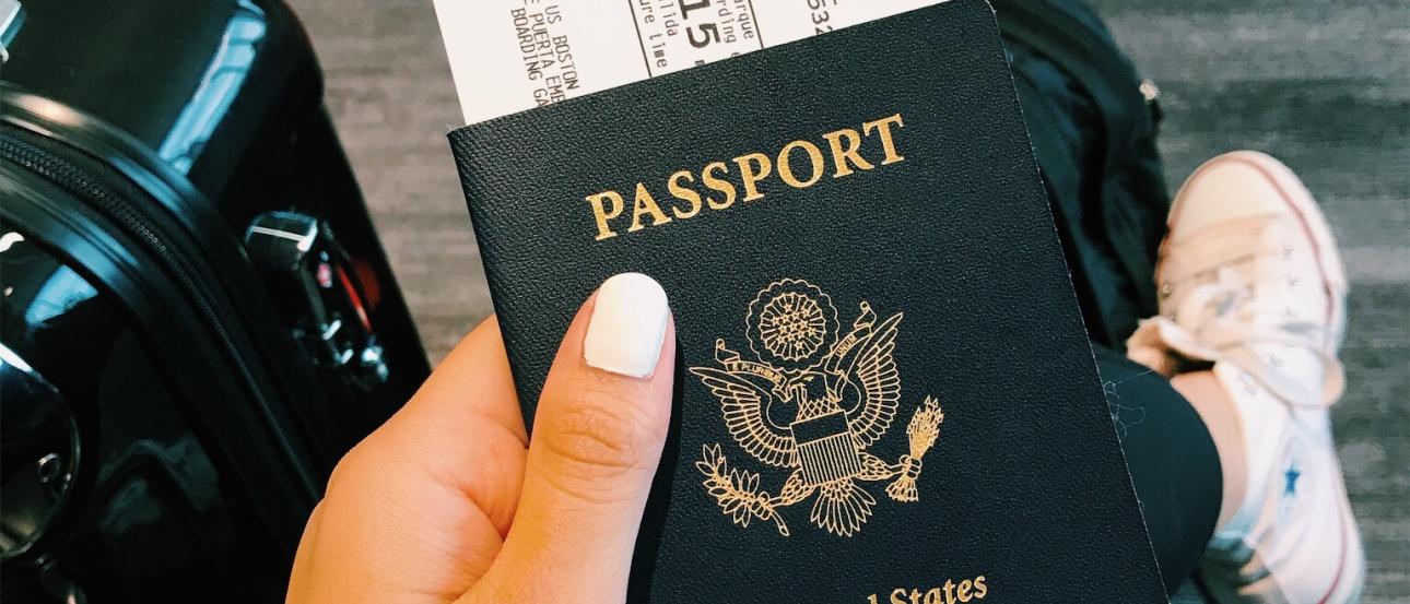 student holding passport in left hand with boarding pass