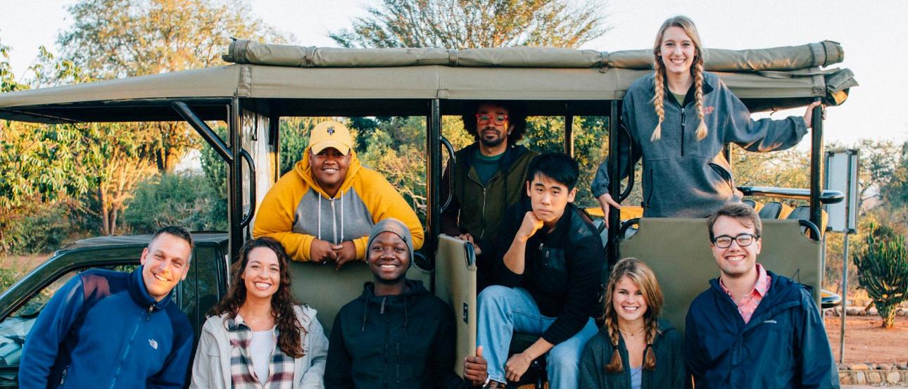 a group of students pose for a photo in their Land Cruiser while on a safari in South Africa