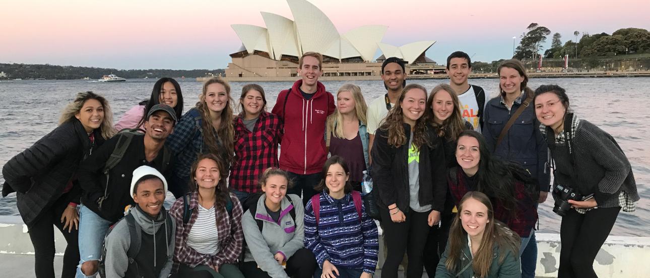 a group of students pose for a photo in front of Sydney Opera House at sunset
