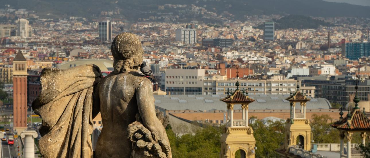 a cityscape of beautiful Barcelona behind a statue