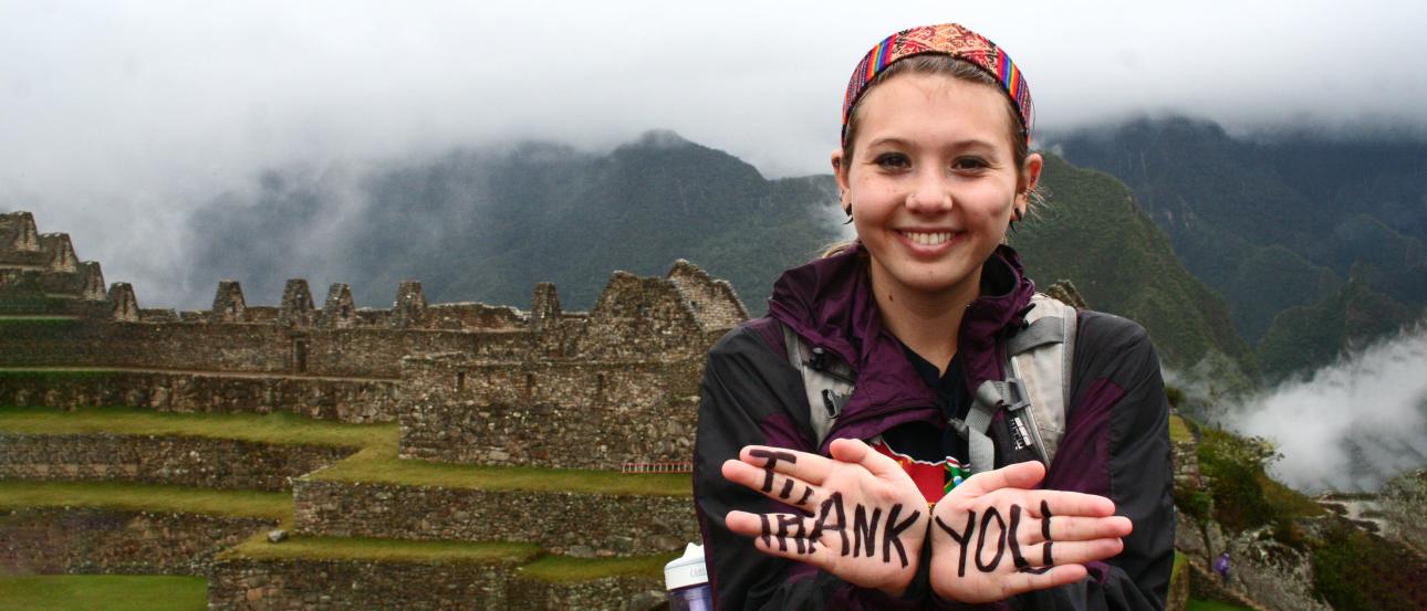 a student visiting Machu Picchu in Peru with "thank you" written on her hands