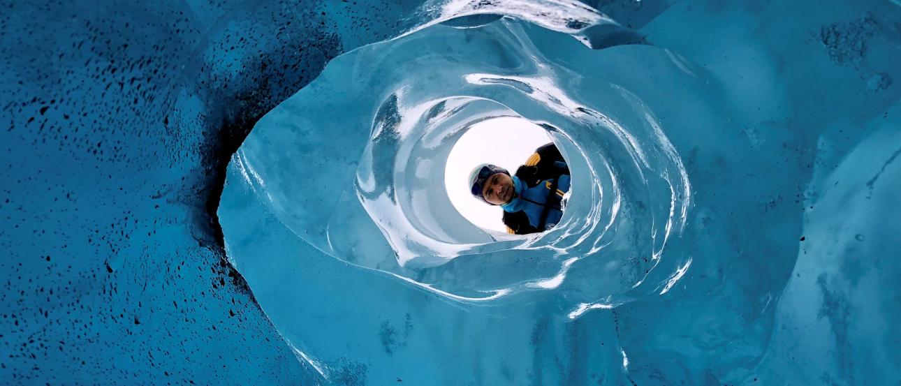 Person looking through a hole in a glacier.