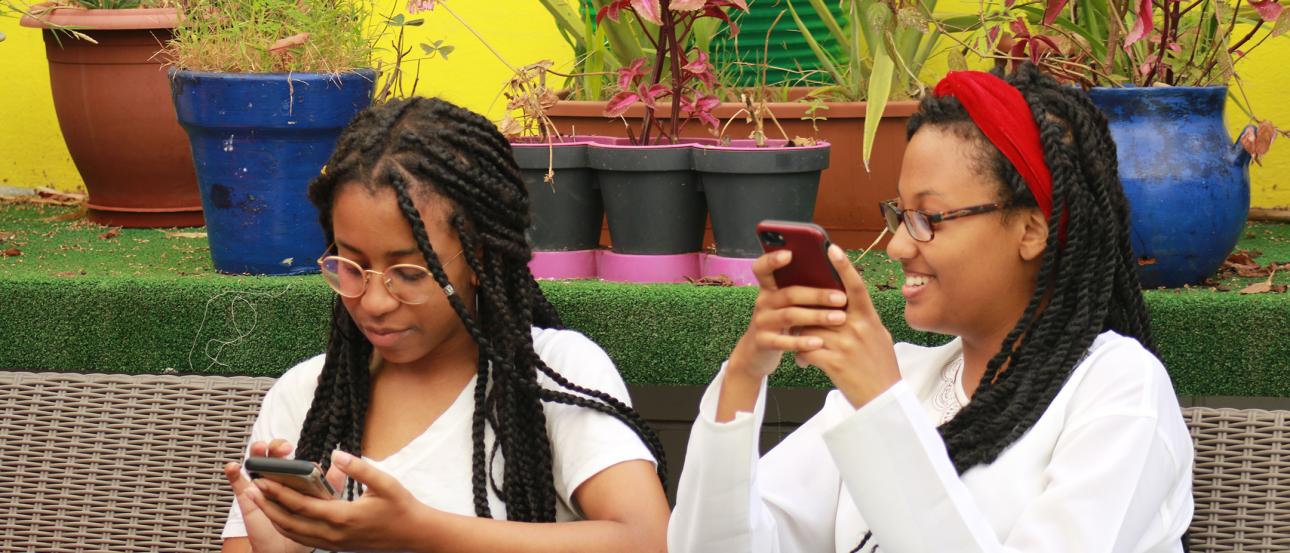 Two students looking at their phones and laughing in Rabat