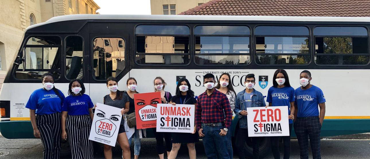 Several students standing in front of a bus holding "End the Stigma" signs