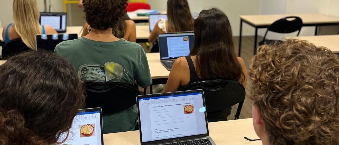 paris students sitting in front of a teacher lecturing while taking notes on laptops
