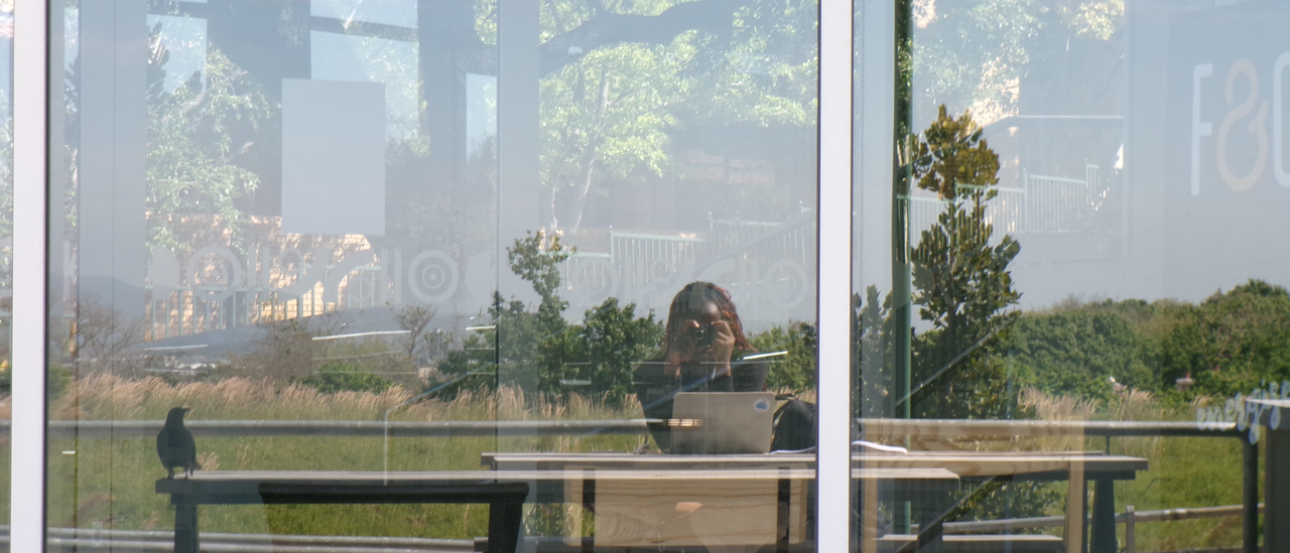Picture of me in the reflection of a building, studying outside. 