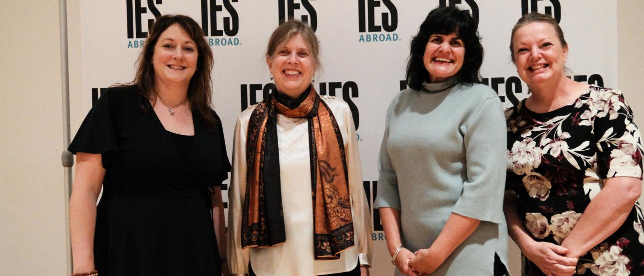 Four smiling women in front of a background that says IES Abroad