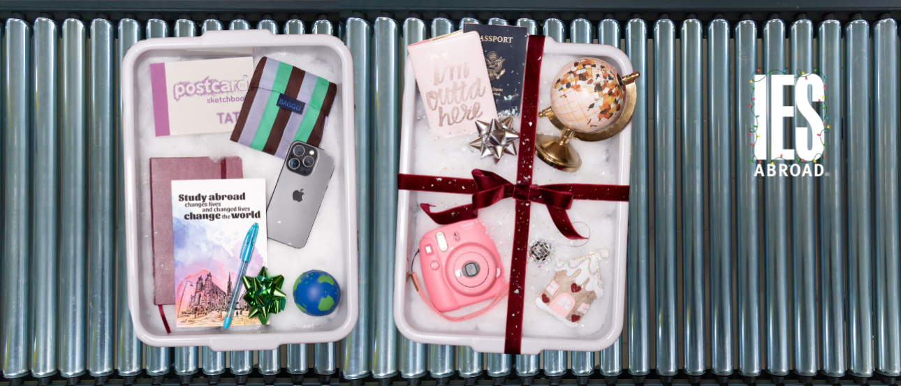 A image of a conveyor belt at an aiport with TSA bins filled with study abroad related items like passports, notebooks, cameras, globes, and an IES Abroad logo with string lights in the corner