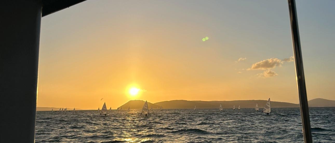 The sunset over the water in Split with boats in the background.