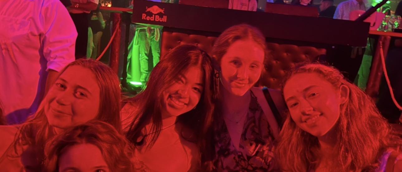 My friends and I smiling at Mae West, illuminated by red lights