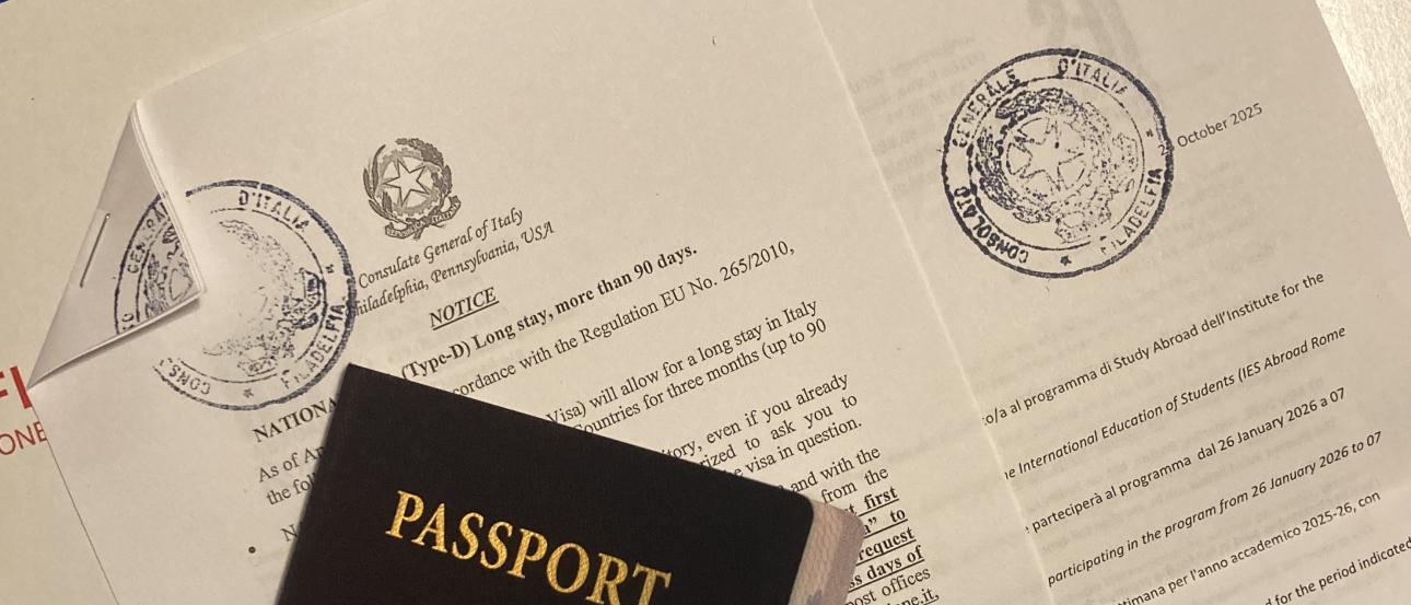 An image of a closed passport with a visa letter and envelope behind it.