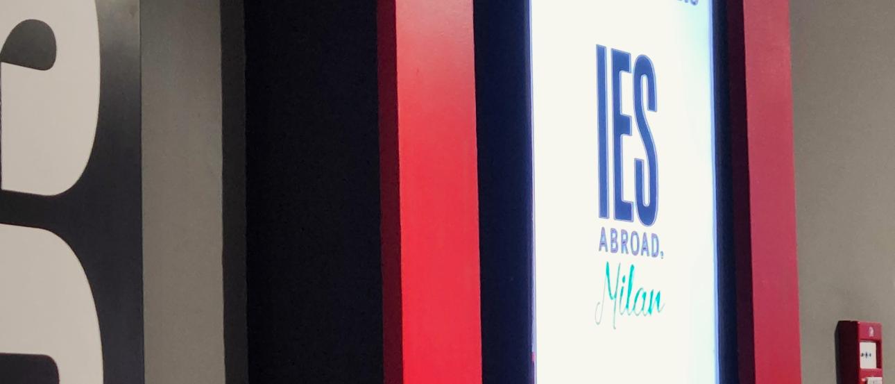 Digital display reading “Welcome to Milano – IES Abroad Milan, Spring 2026” inside a building lobby.