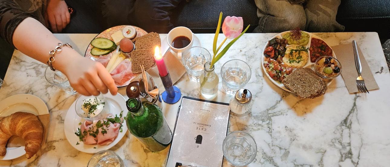 An image of a table at a café, where all sitting bodies have a plate of food except for the photographer.