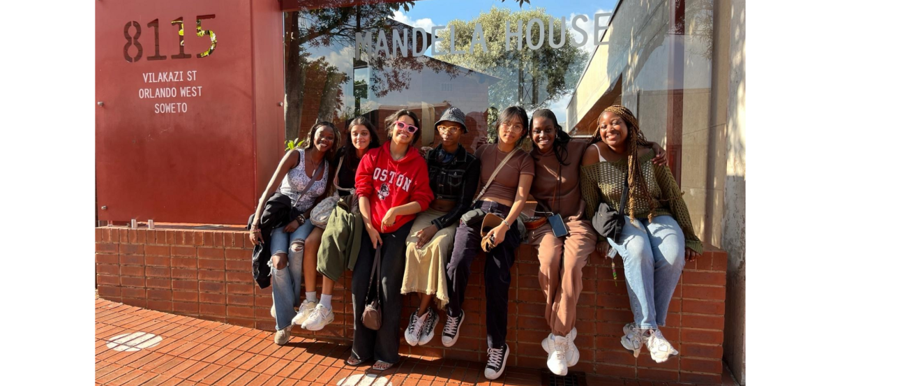 Group of students sitting outdoors smiling on a sunny day