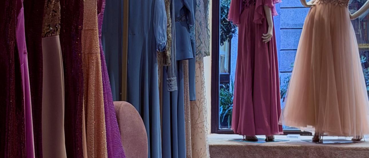 The center of the main room in the Atelier. A row of gowns on the left hand side range in colors of purple to pink 