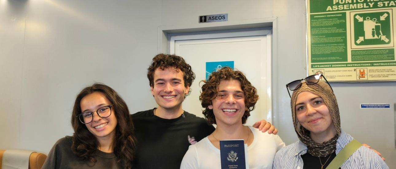A group of friends smiling and one is holding up a passport.